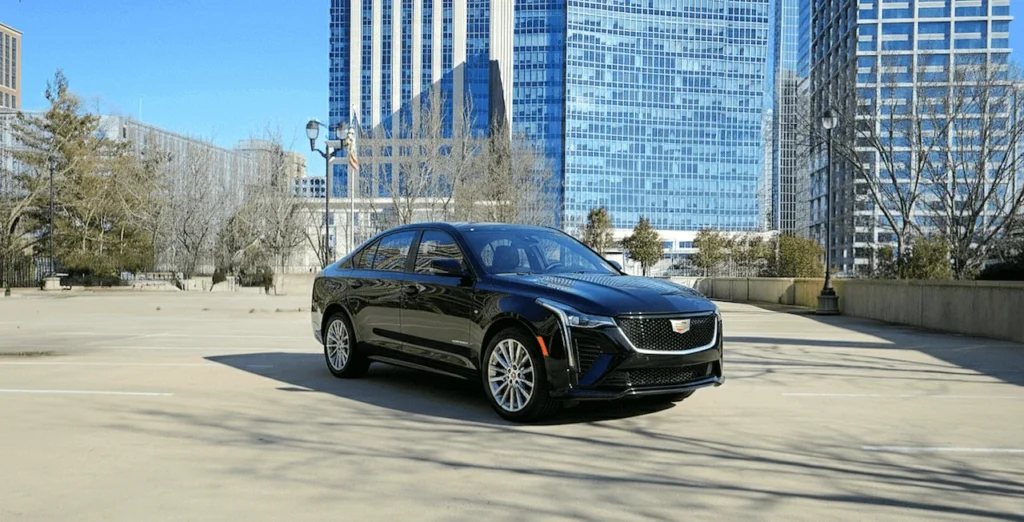 Luxury sedan cruising through urban setting for VOY Black Car service.